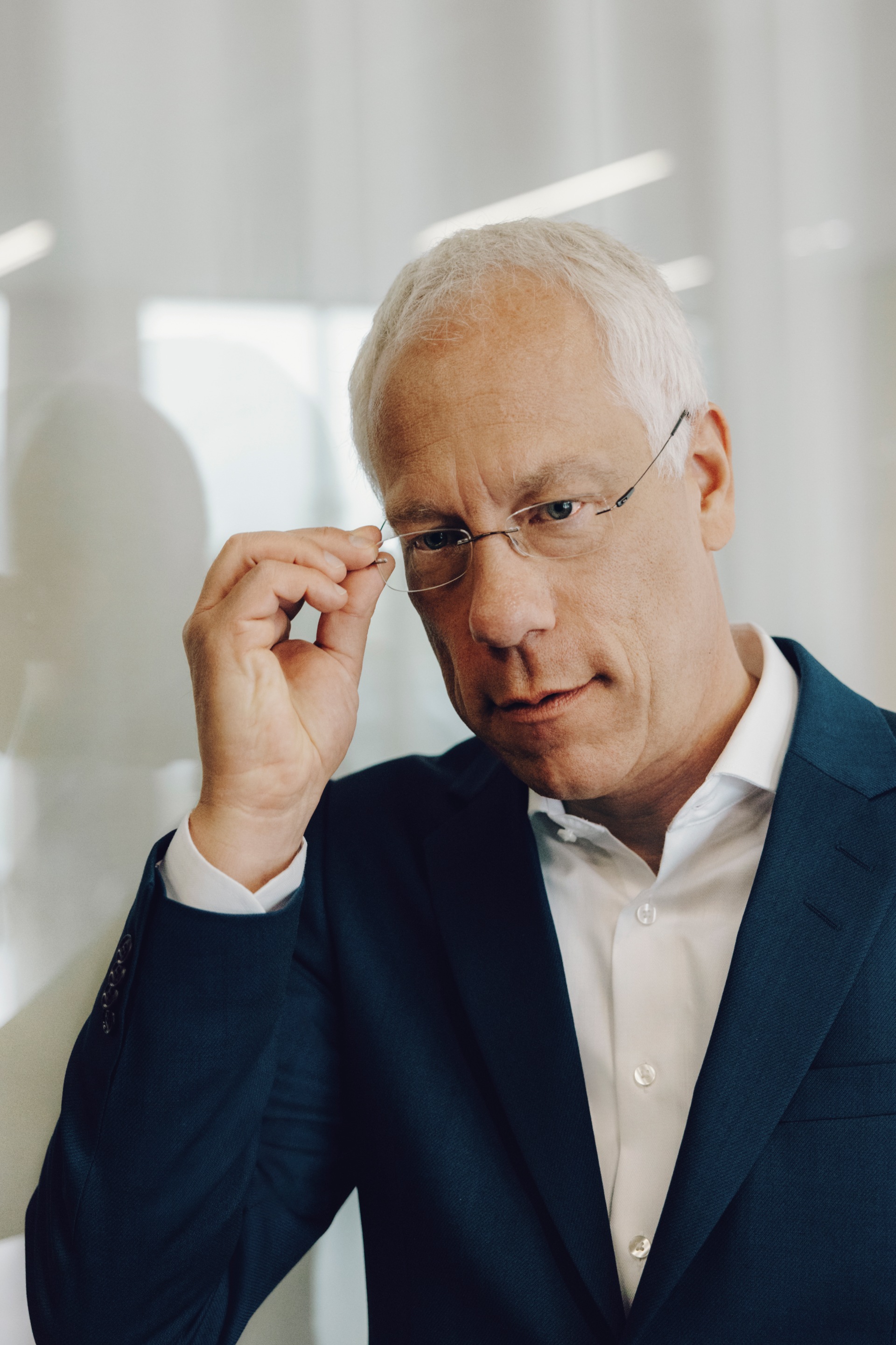 Peter Gladbach touche ses lunettes pendant qu'il regarde la caméra.