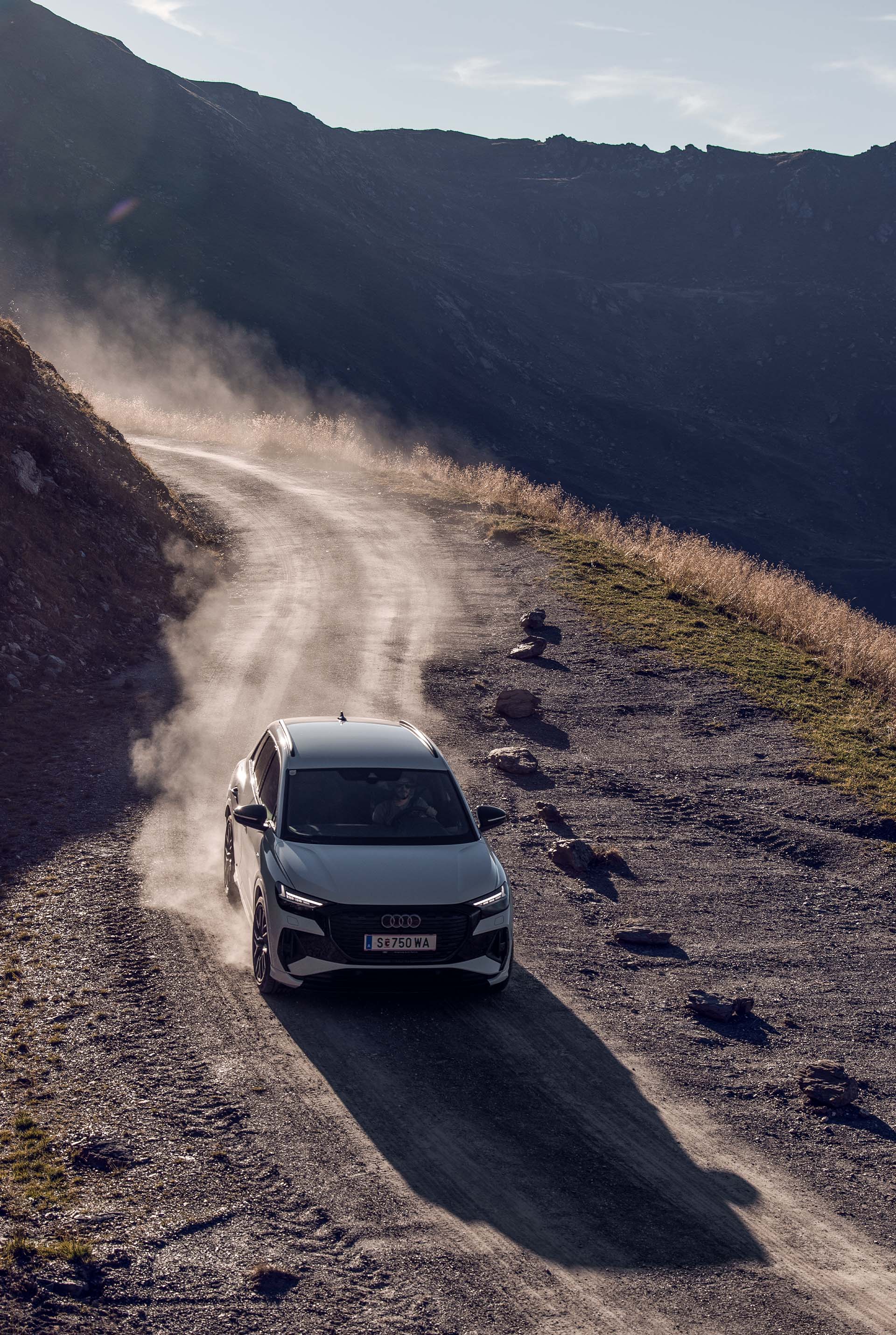 Een witte Audi Q4 e-tron rijdt een bergweg omlaag.