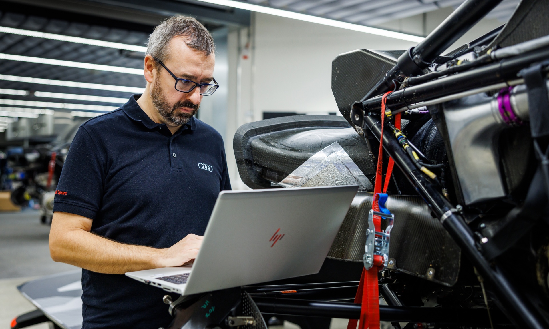 Arnau Niubó Bosch travaillant sur un ordinateur à côté de l'Audi RS Q e-tron démontée.