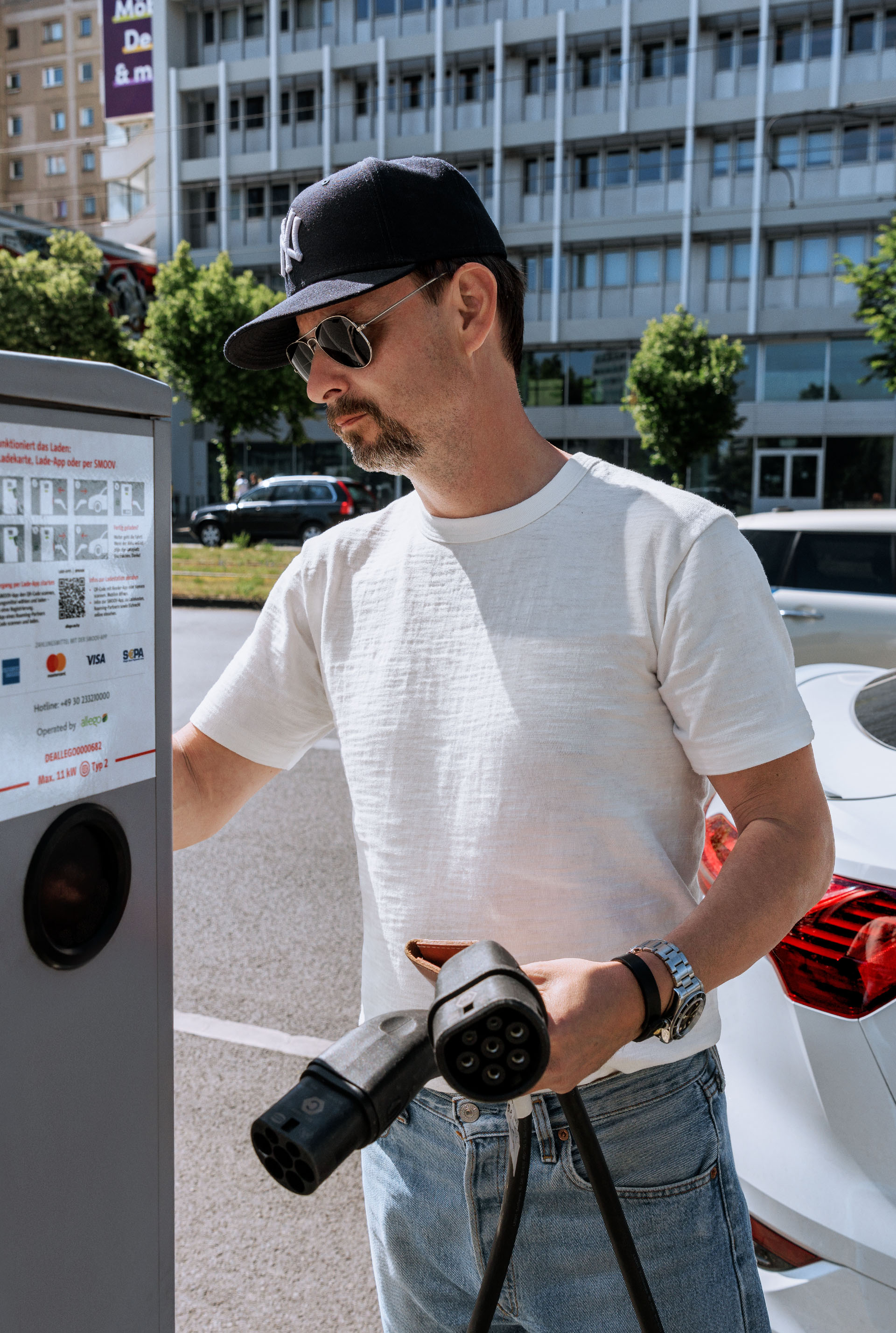 Gros plan sur la main de Marco Voigt lorsqu'il introduit le câble de recharge dans le véhicule électrique. 